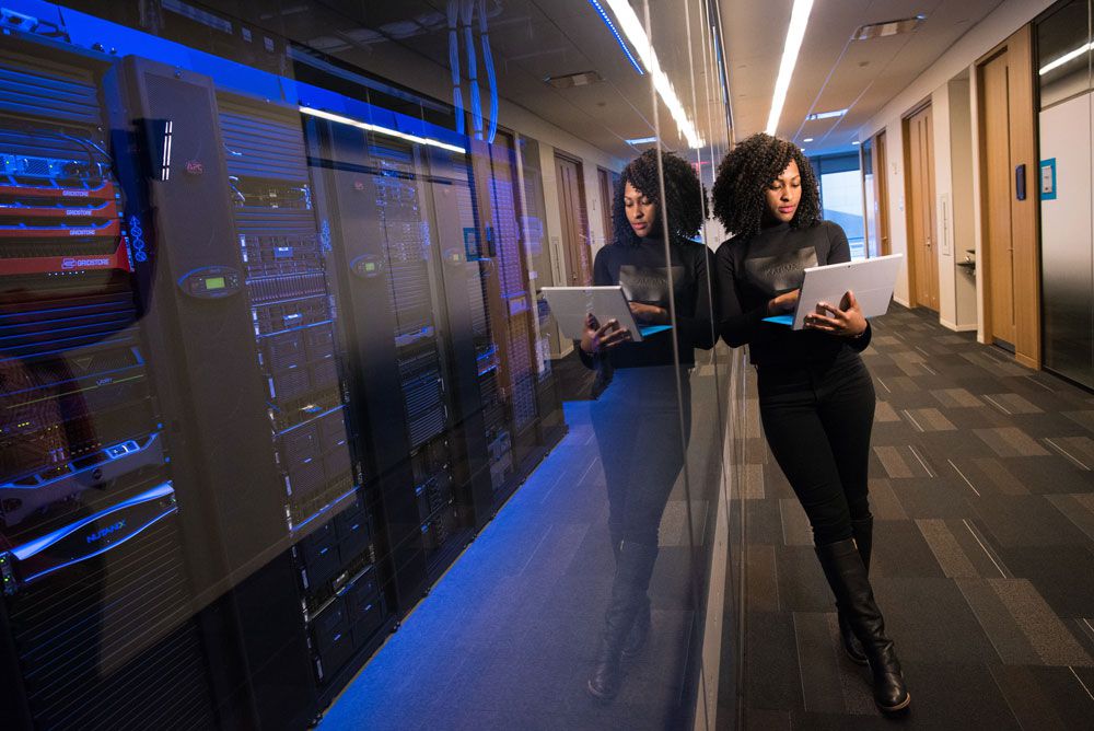 A woman with a laptop standing in a corridor